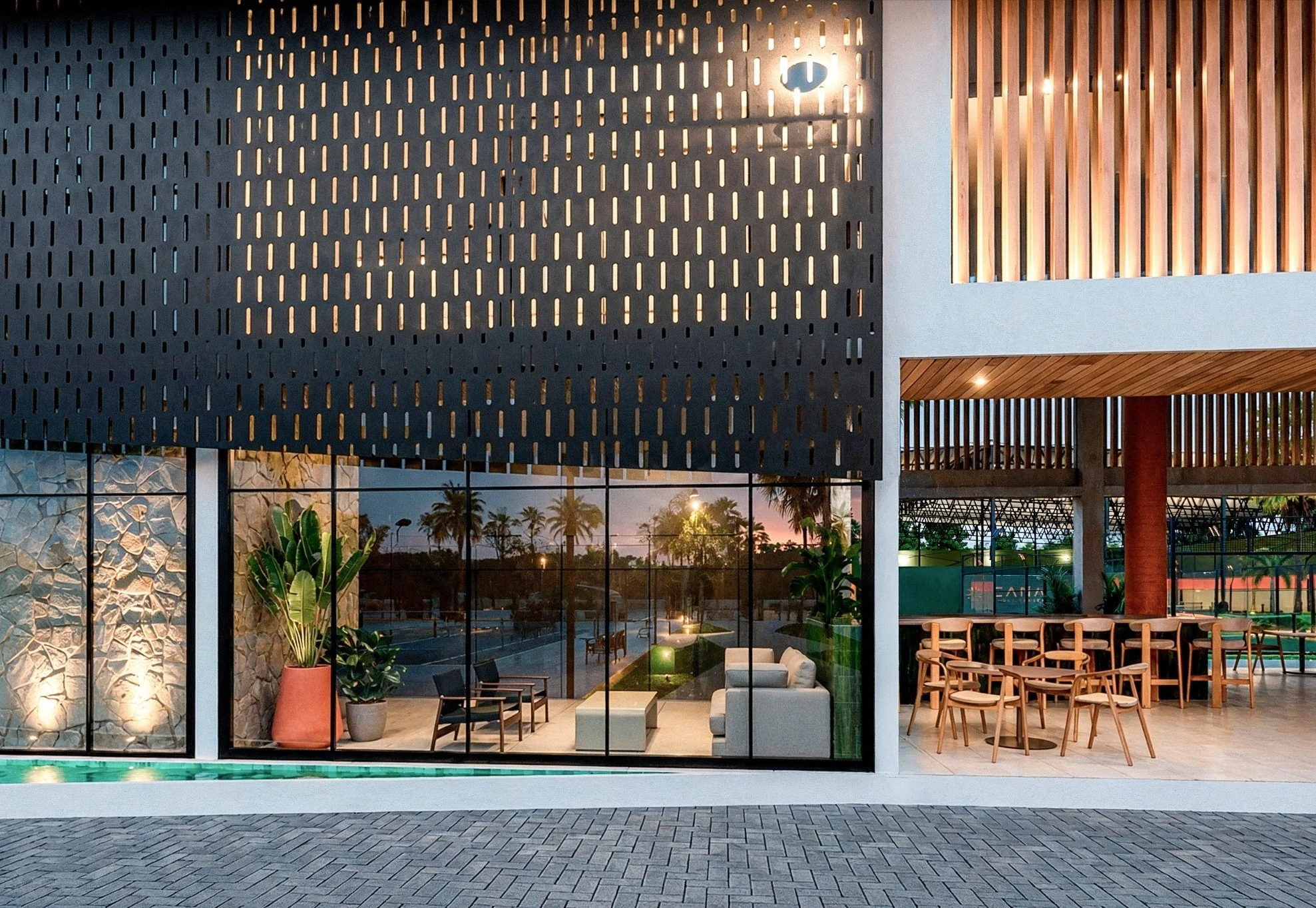 Fachada de Cana Sport Center con celosía, vegetación y área social