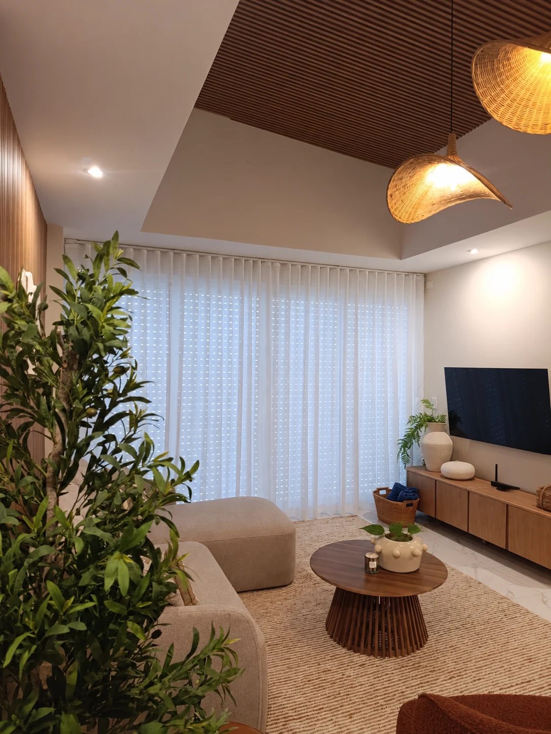 Sala terminada con iluminación cálida, cortinas, mobiliario y vegetación