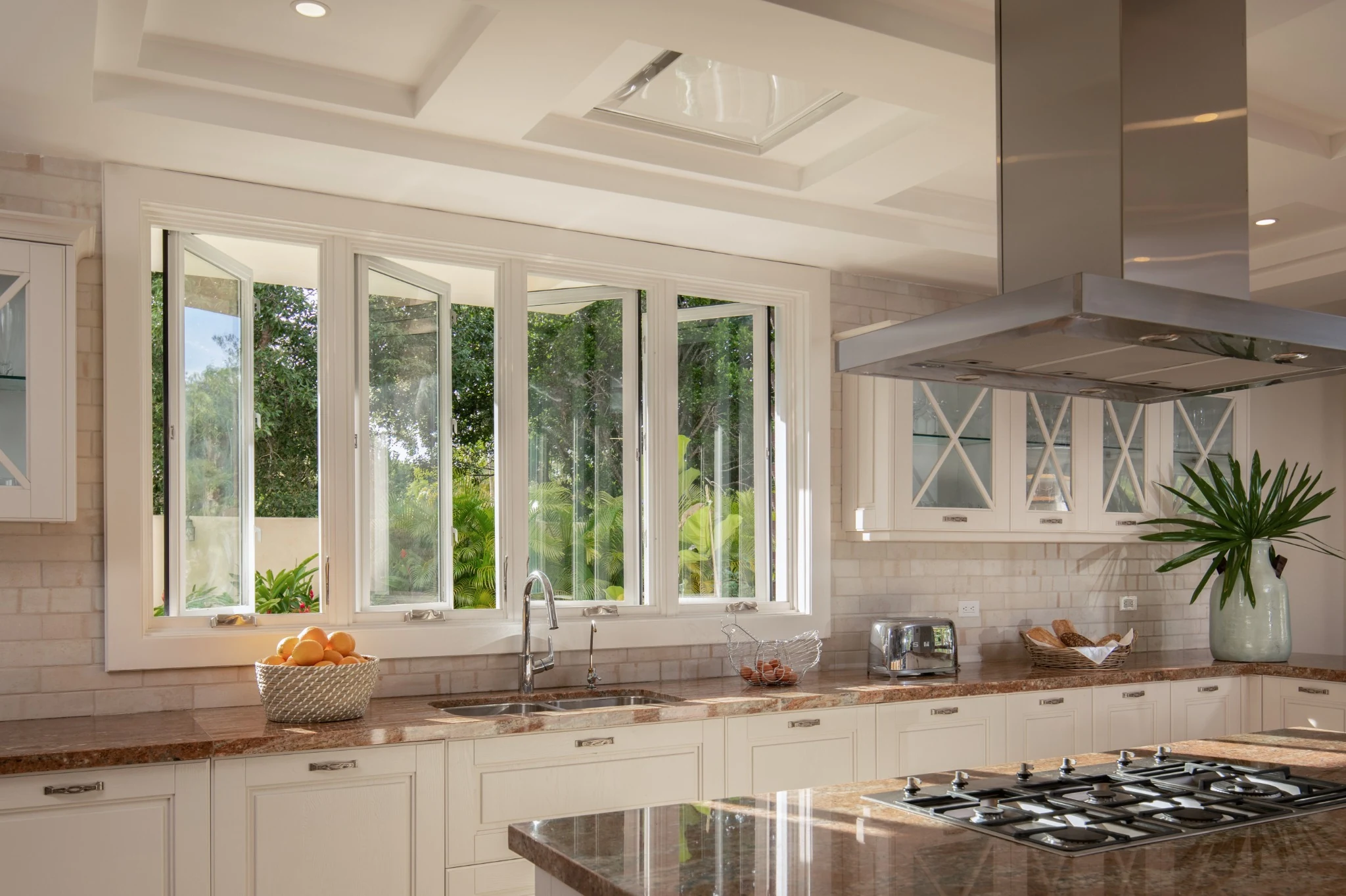 Cocina con mobiliario claro, isla y ventanas hacia el jardín